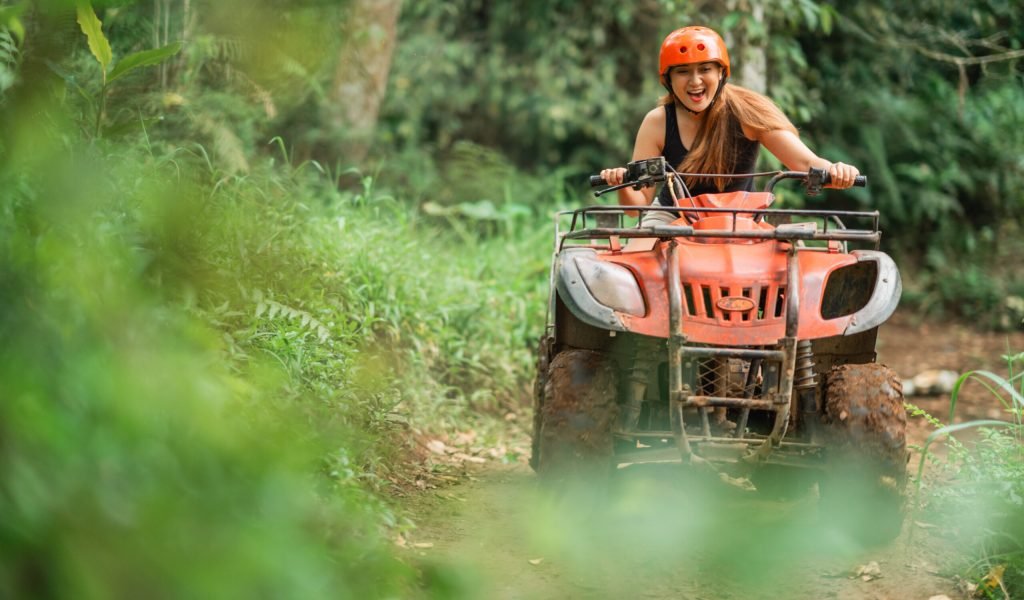 beautiful asian woman riding the atv happily through the atv arena spending her holiday